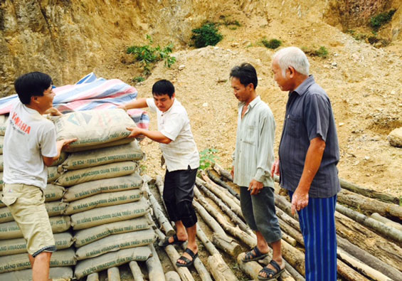  Ông Lã Viết Thụ (ngoài cùng bên phải) hướng dẫn người dân tập kết vật liệu xây dựng chuẩn bị làm đường giao thông nông thôn.