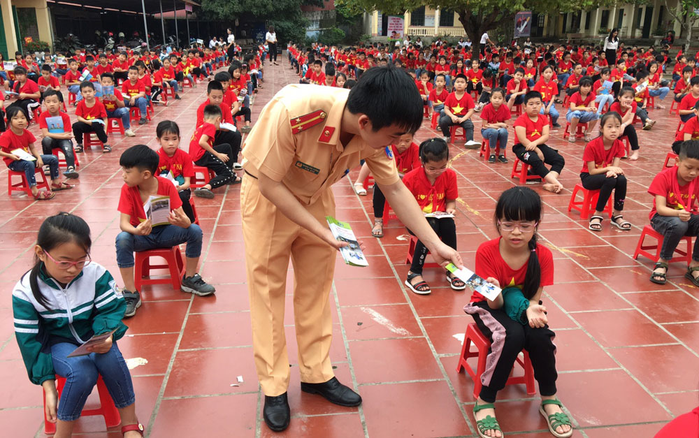  Cán bộ Cảnh sát Giao thông Công an huyện Đồng Hỷ phát tờ rơi tuyên truyền Luật Giao thông cho các em học sinh.