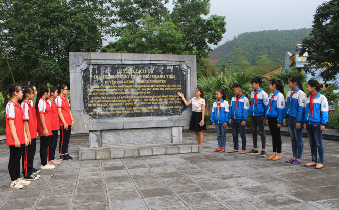 Cô Nguyễn Thị Minh, Phó Hiệu trưởng Trường THCS Giang Tiên giới thiệu với các em học sinh về di tích Xưởng Quân giới - nơi sản xuất thành công súng Bazôka của Quân đội ta - nằm sát địa điểm của Nhà trường.