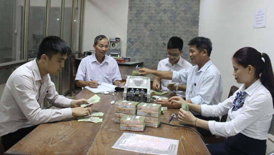  Anh Bùi Tiến Đông (người cầm bút) chứng kiến việc kiểm đếm giao nhận tiền cho khách hàng tại Phòng Tiền tệ - Kho quỹ.