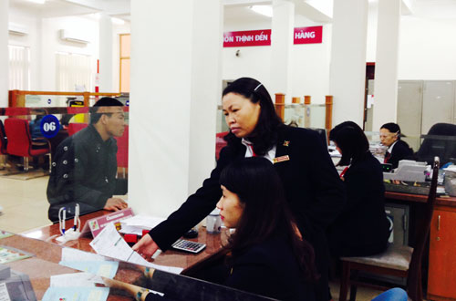  Chị Dương Thị Miền (người đứng) kiểm tra cán bộ tín dụng trong việc nhập số liệu của khách hàng vào máy vi tính.