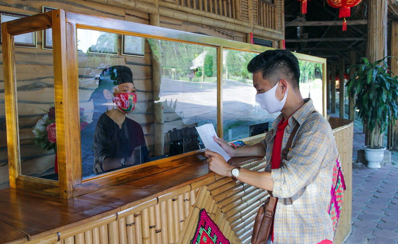  Các khu, điểm du lịch, cơ sở lưu trú, cơ sở kinh doanh và dịch vụ du lịch trên địa bàn đã nghiêm túc triển khai công tác phòng, chống dịch COVID-19. Trong ảnh: Nhân viên Khu bảo tồn làng nhà sàn sinh thái Thái Hải và du khách tuân thủ đeo khẩu trang trong giao tiếp.