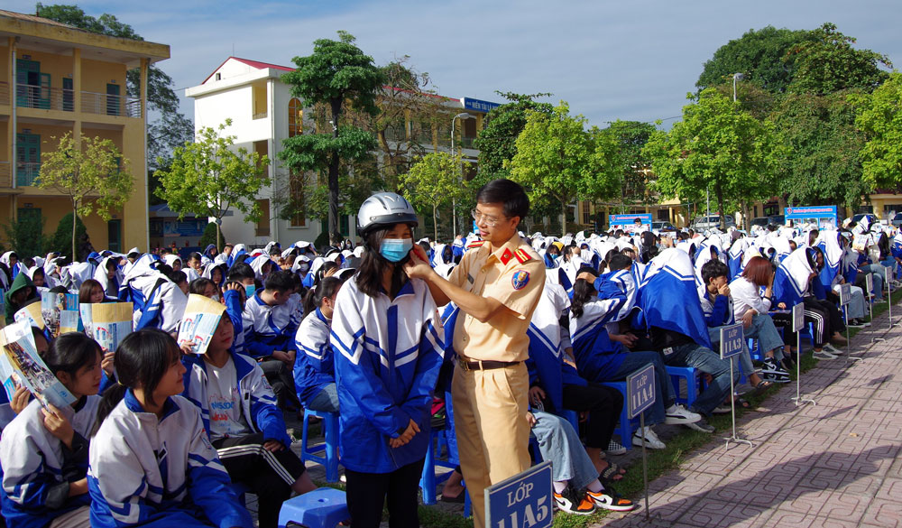   Cán bộ Phòng Cảnh sát giao thông hướng dẫn học sinh sử dụng mũ bảo hiểm đúng cách.