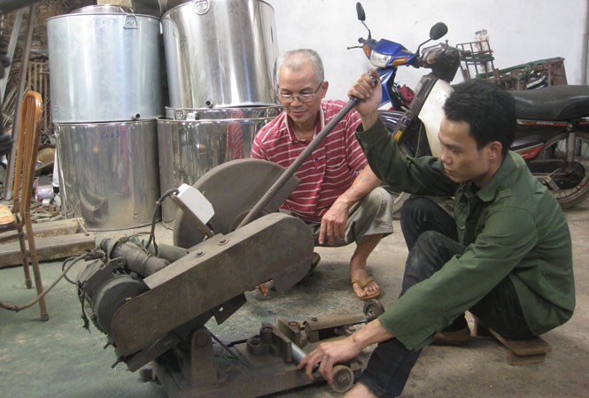  Ông Vũ Văn Sơn (bên trái) hướng dẫn cho người lao động thực hành việc cắt, dập vật liệu phục vụ lắp máy.