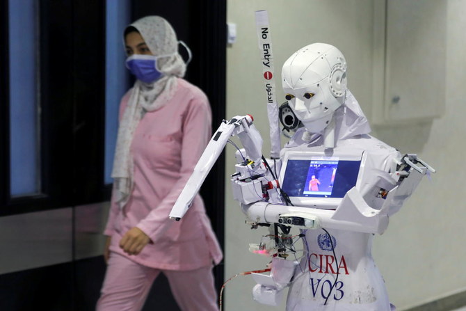  Robot Cira 3 được điều khiển từ xa để xét nghiệmbệnh nhân nghi mắc COVID-19 được nhìn thấy bên cạnh một nhân viên y tế trong hành lang của bệnh viện, giữa làn sóng đợt dịch thứ hai ở Tanta, Ai Cập, ngày 18-11. Ảnh: Reuters.