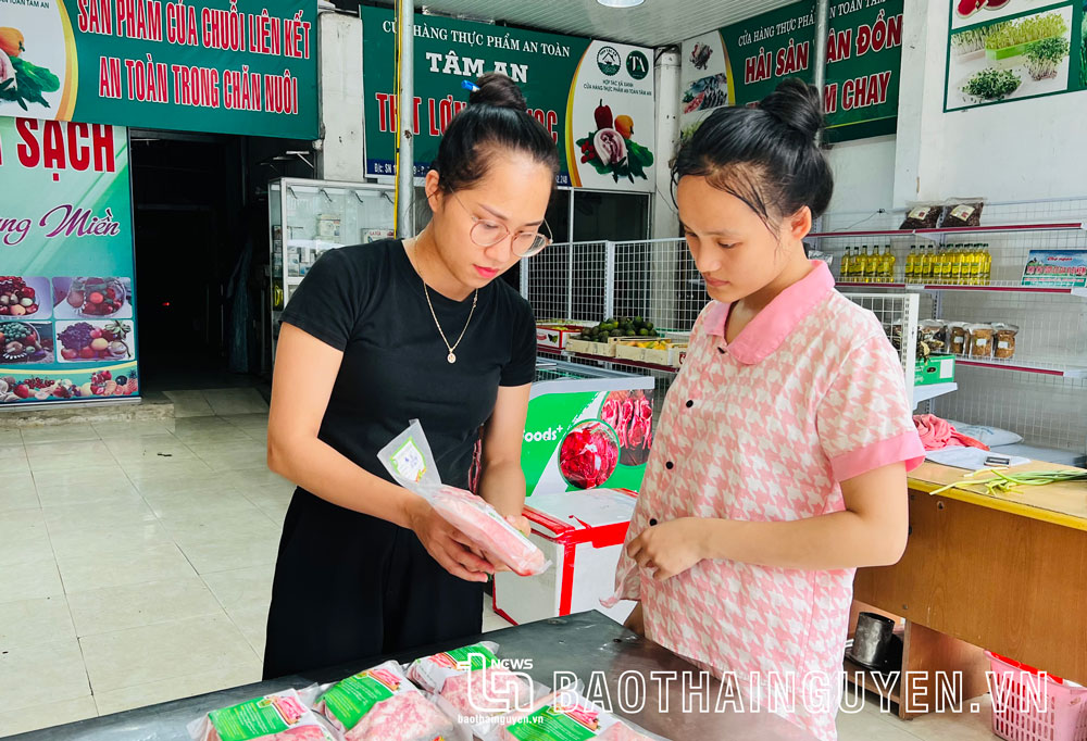 Nhân viên cửa hàng thực phẩm an toàn Tâm An của HTX Xanh giới thiệu sản phẩm cho khách hàng.