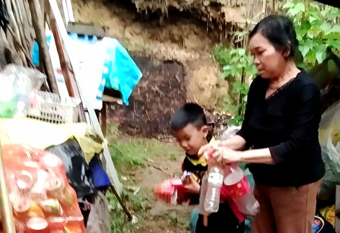  Bà Ngô Thị Thảo cùng cháu ngoại bên những chai lọ vừa nhặt về để đem bán kiếm tiền nuôi nhau qua ngày.                                         