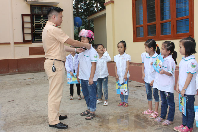  Cán bộ Đội Cảnh sát giao thông - Trật tự (Công an huyện Võ Nhai) hướng dẫn học sinh Trường Phổ thông dân tộc nội trú Tiểu học Sảng Mộc đội mũ bảo hiểm đúng cách.