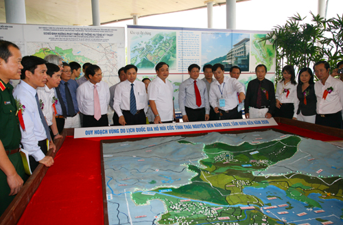  Deputy Prime Minister Hoang Trung Hai and delegates ar listening to the introduction about the plan of national tourism area of Nui Coc Lake through the model